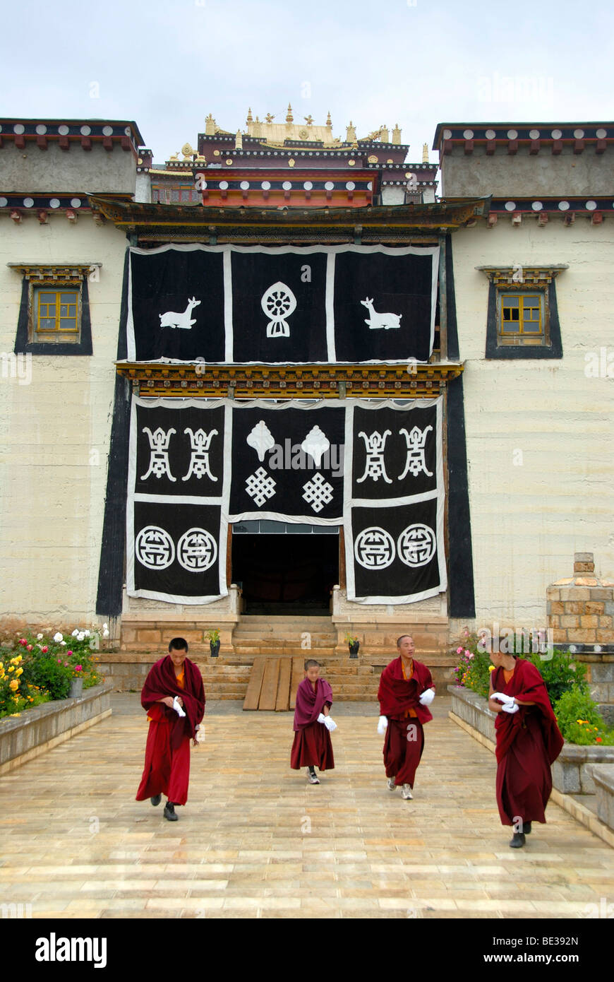 Tibetan Buddhist, monks in red robes, temple with entrance portal, religious symbols, Monastery Ganden Sumtseling Gompa, Zhongd Stock Photo