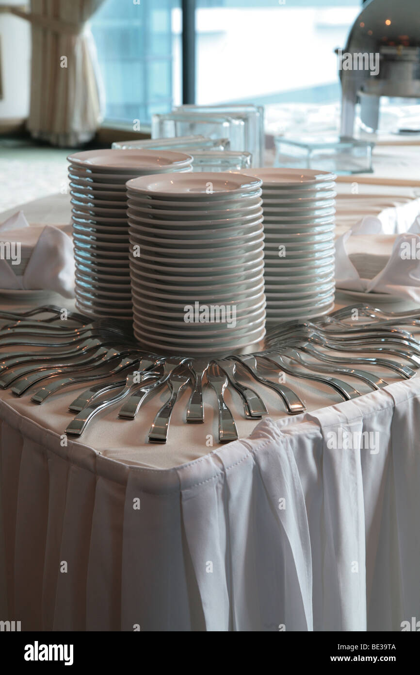 Stack of ceramic plates and forks for serving a buffet at a hotel Stock