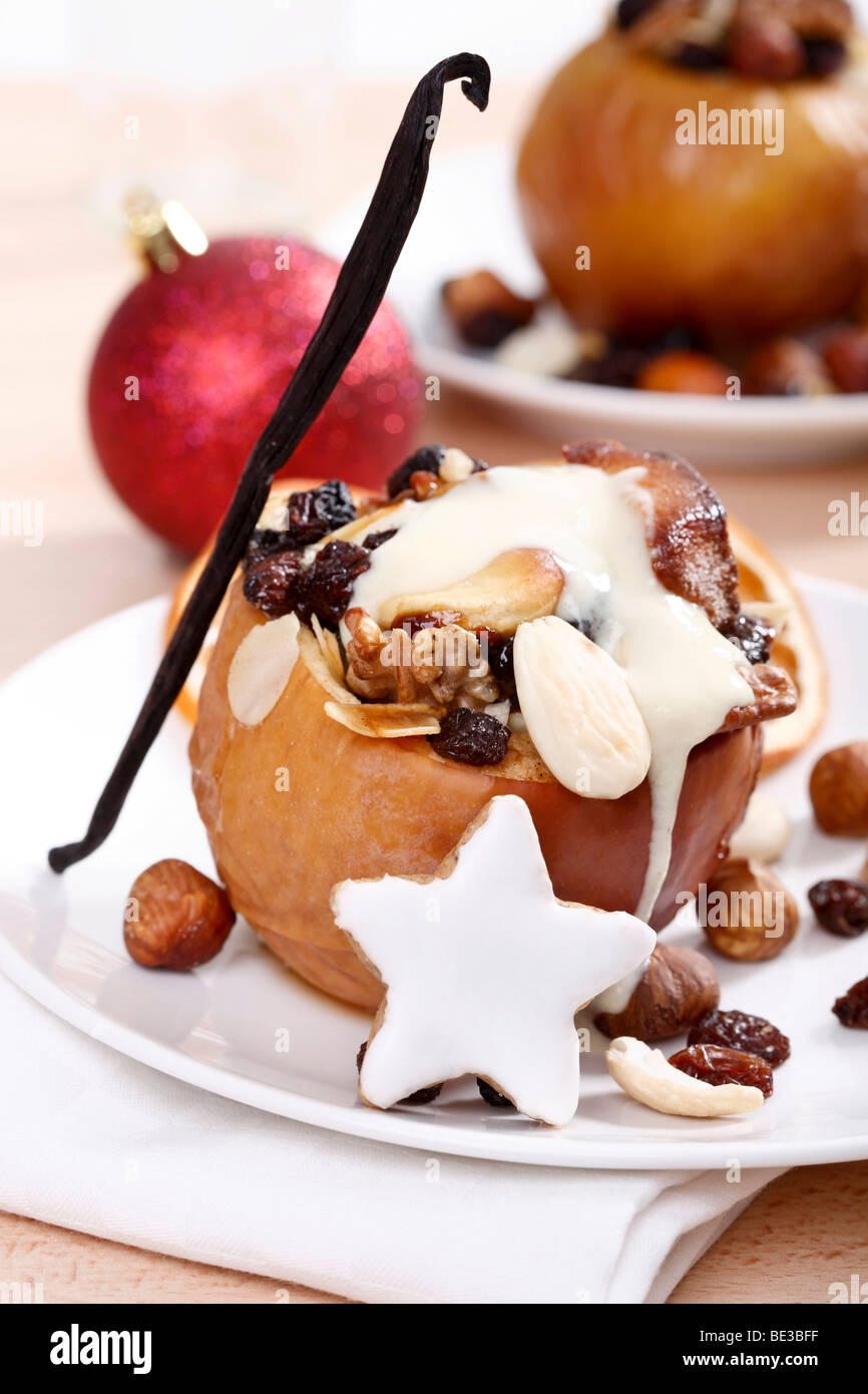 Baked apple with vanilla sauce, filled with nuts, marzipan and rainsins, festive atmosphere Stock Photo