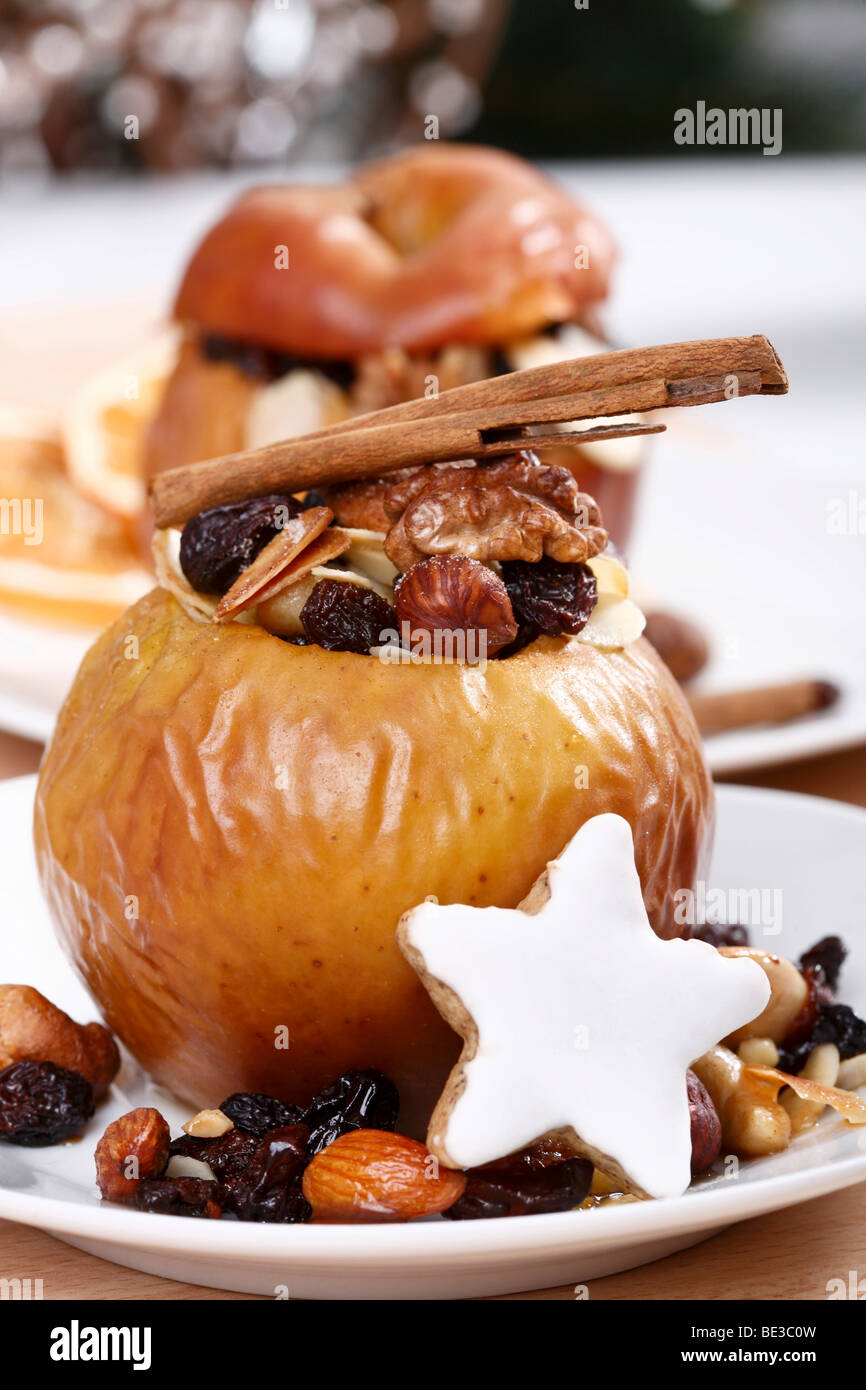 Baked apple with raisins, nuts, marzipan, cinnamon stick and Zimtstern, cinnamon biscuit, in festive atmosphere Stock Photo