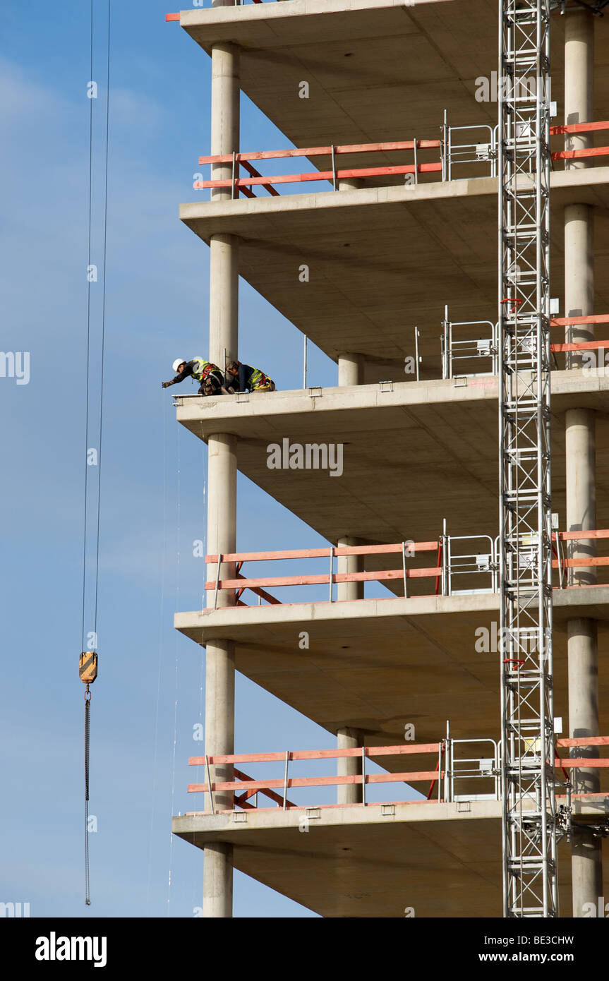 Construction workers fitting safety rails to s partly built office ...
