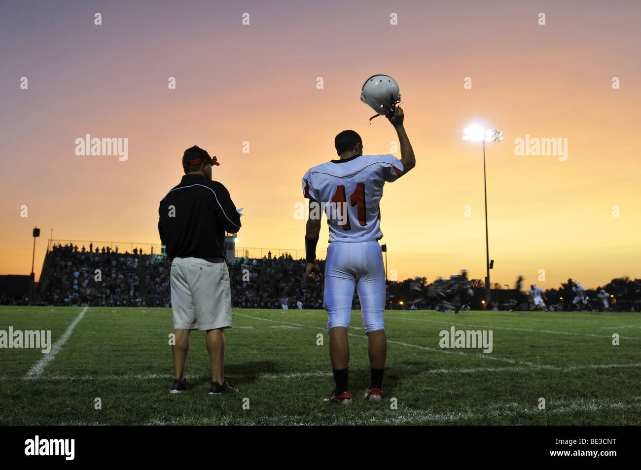 Football game at a high school with player and coach watching Stock Photo