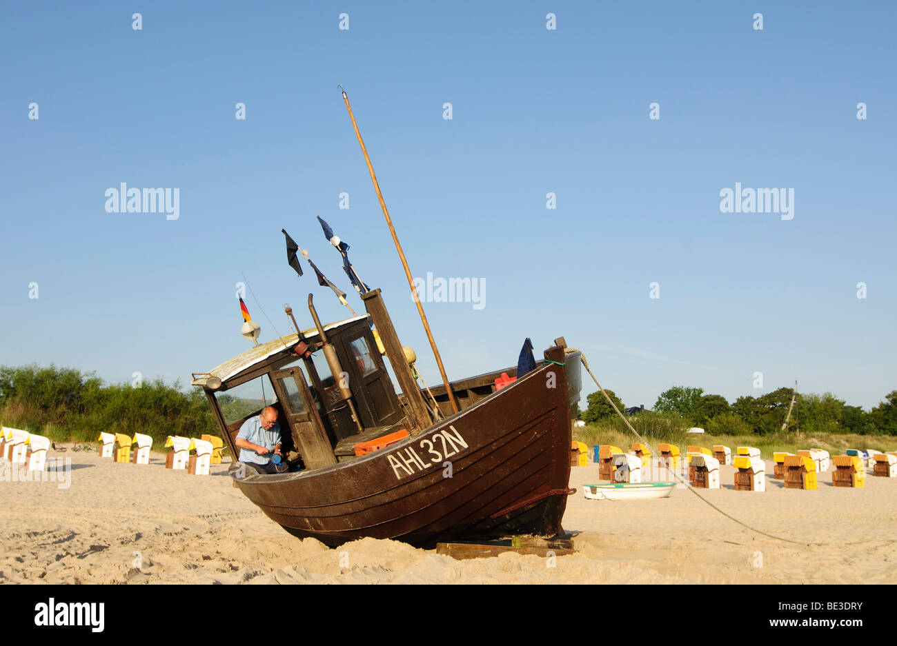 A Fisherman Works On His Fishing Boat On The Beach In The Seaside