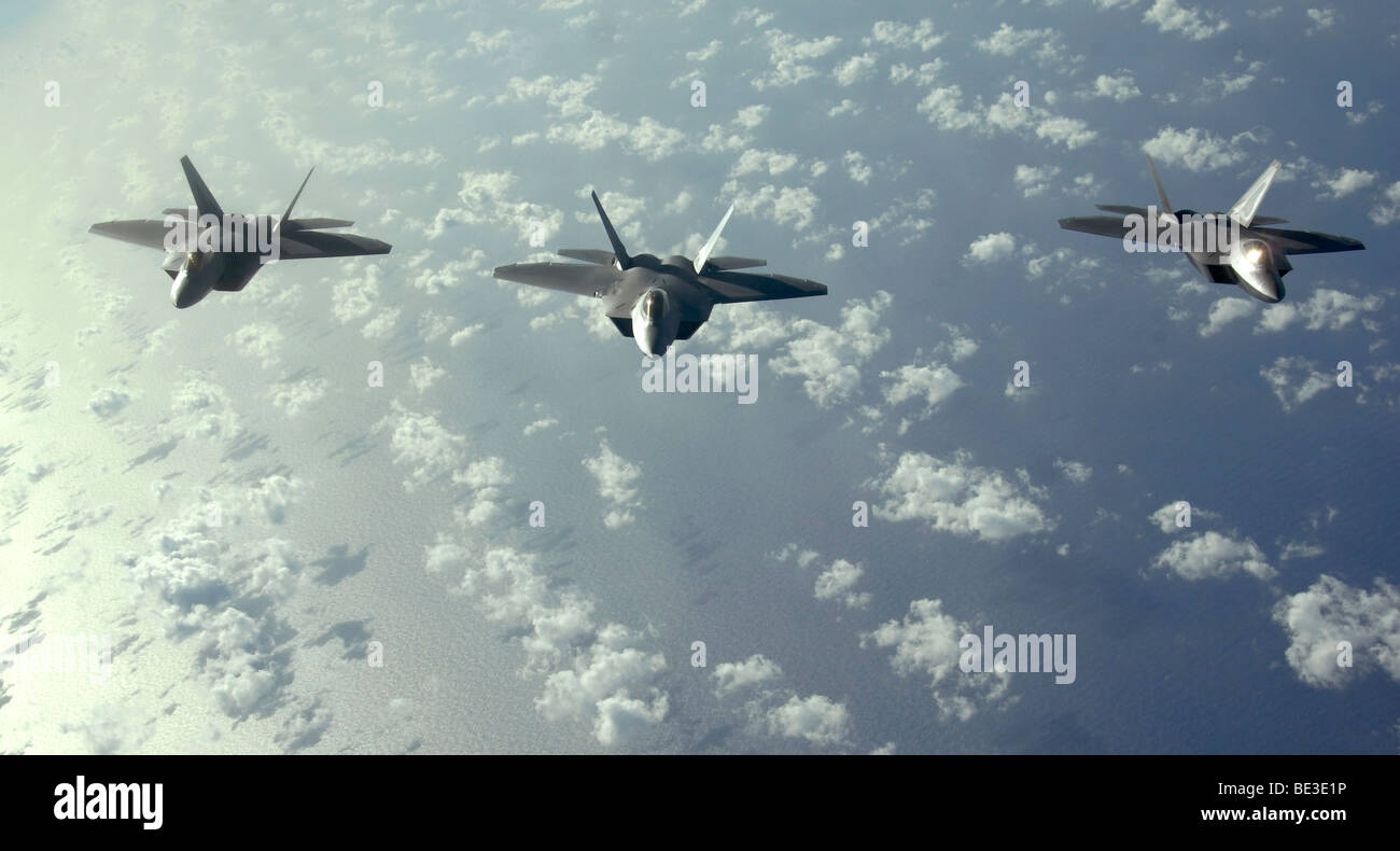 A three-ship formation of F-22 Raptors fly over the Pacific Ocean during a Pacific theater mission. Stock Photo