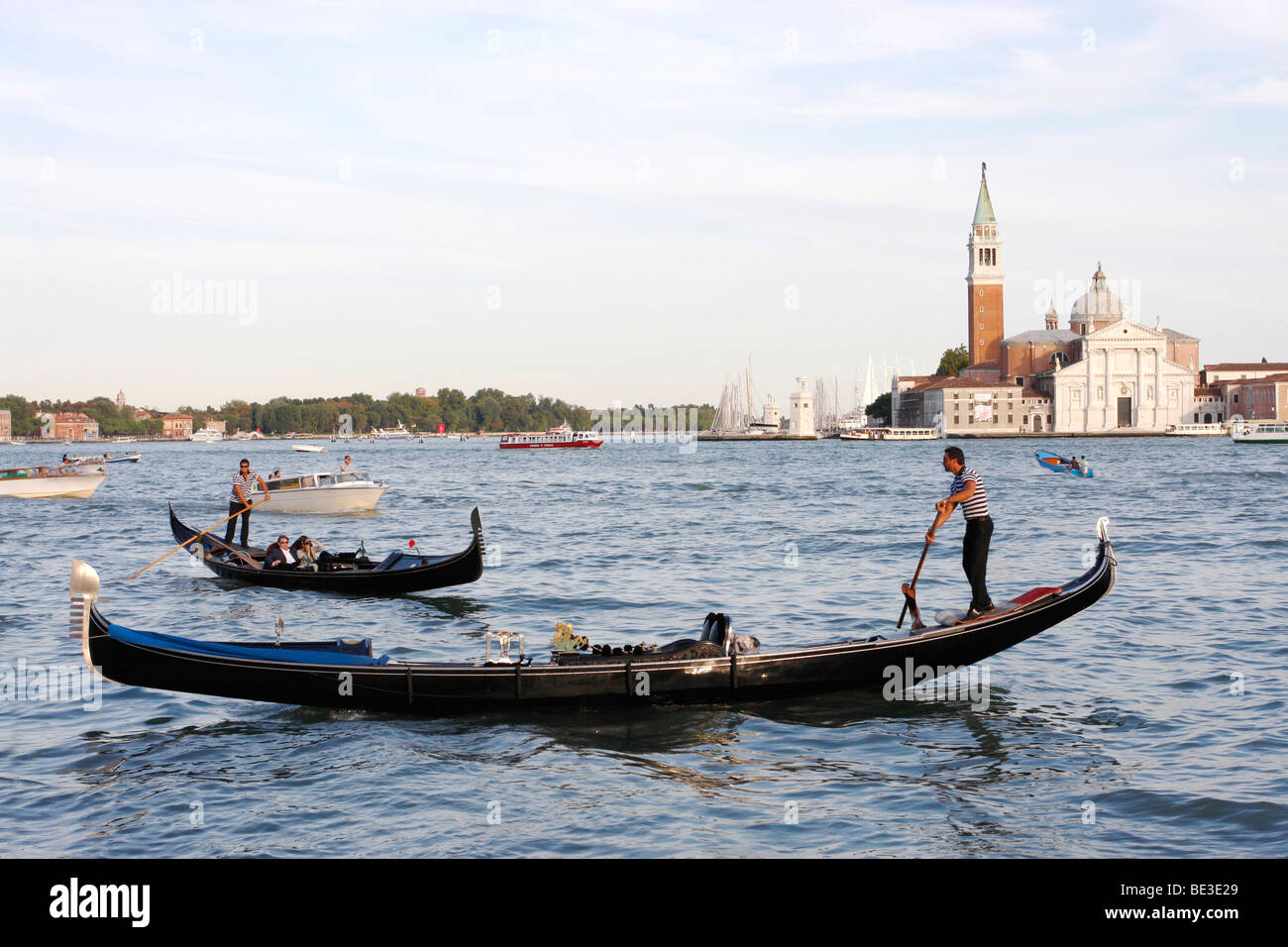 Gondolier 's paddle their craft in front of the San Giorgia Maggiore Island  opposite   St Marco's square.Venice. Stock Photo