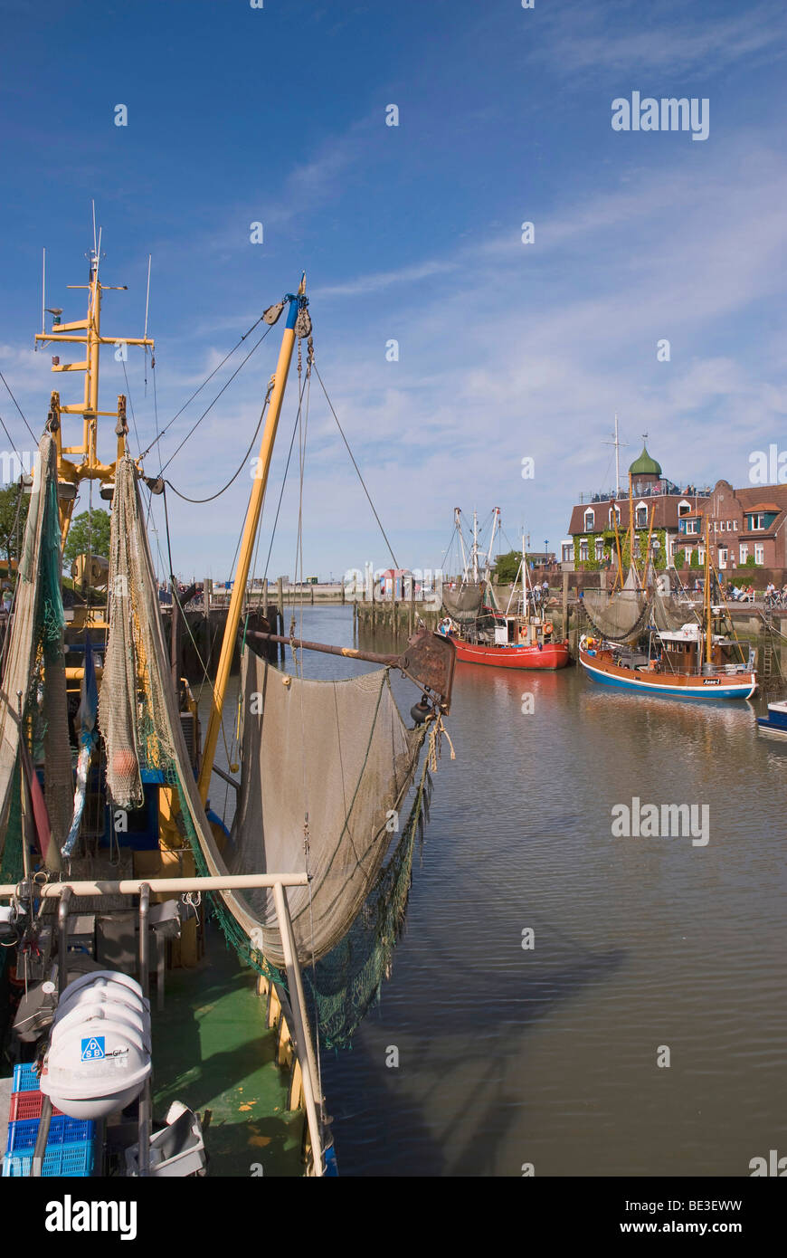 Shrimp cutter in the harbor of Neuharlingersiel, cutter with pulled-up fishing gear in front, Wadden Sea National Park, East Fr Stock Photo