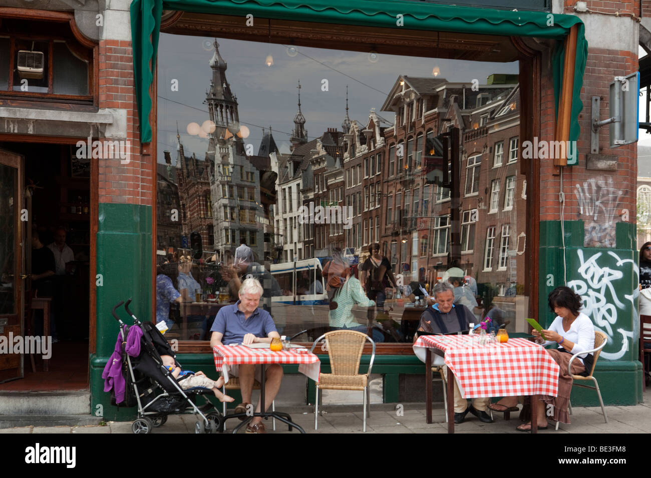 Restaurant with tables outdoor in the street and reflection of the traditional houses in the window. Amsterdam, Holland Stock Photo