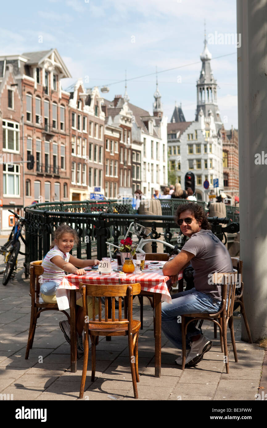 Family of tourists having lunch in the street of Amsterdan by a canal bridge. Holland Stock Photo