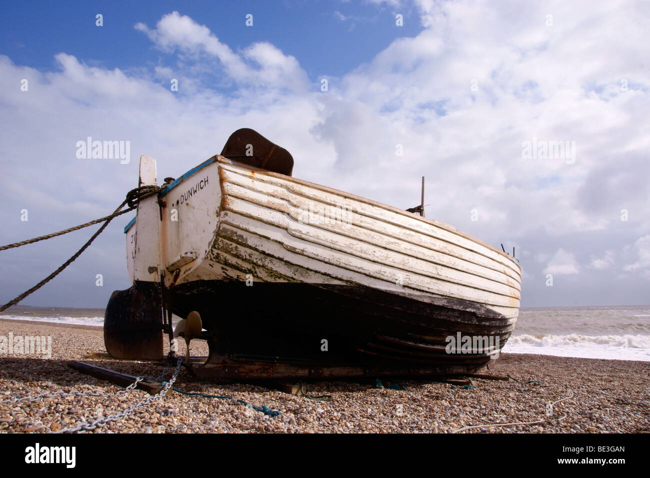 A white wooden fishing boat pulled up onto a shingle beach Stock Photo ...