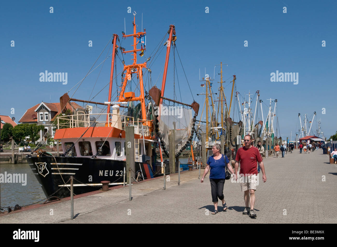 Tourists next to the fleet of shrimp boats in the harbor Neuharlingersiel, North Sea, East Frisia, Lower Saxony, Germany, Europe Stock Photo