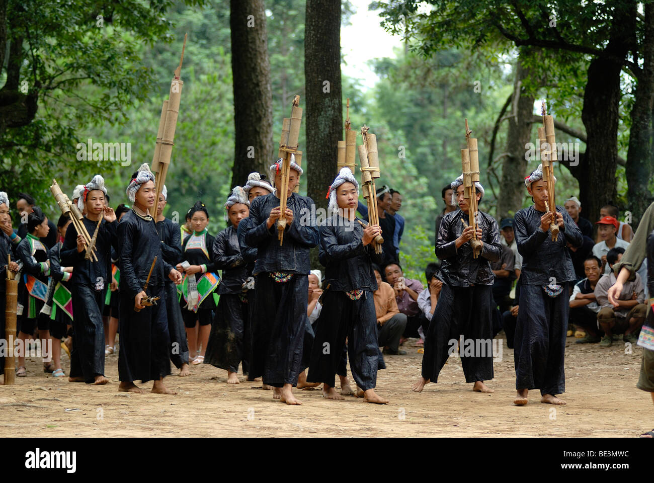 Men and woman in a Lusheng orchestra in costume of the Basha minority from beaten black cotton with bamboo flutes and mouth org Stock Photo