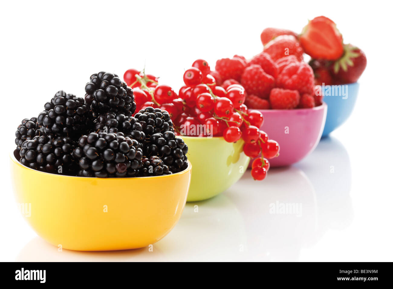 Wild berries in colourful bowls, raspberries, blackberries, blueberries, currants, strawberries Stock Photo