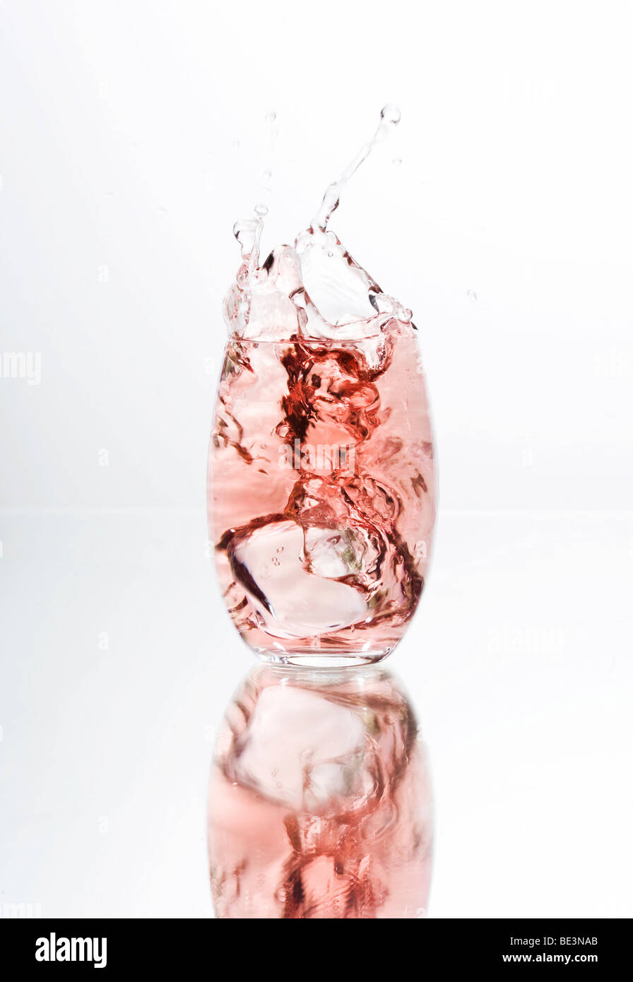 Ice cube falling in a glass of red liquid, juice, cocktail Stock Photo