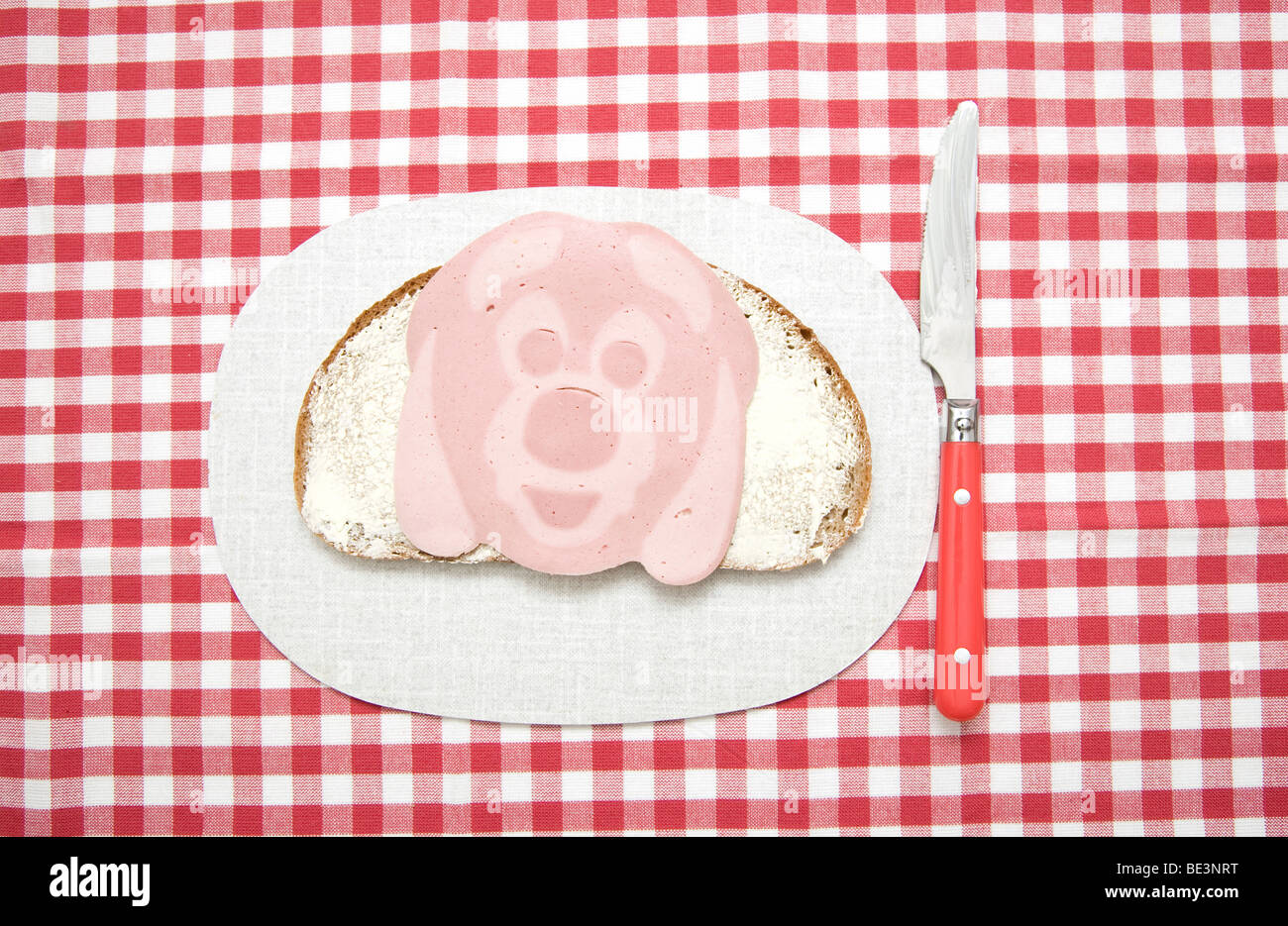 Sandwich with sausage in the form of a face, a dog's head on board with knife Stock Photo