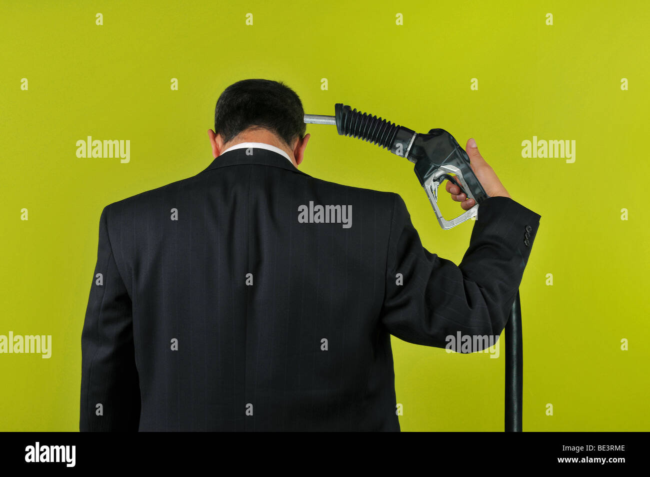 Businessman committing suicide with a gas nuzzle isolated on a green background Stock Photo