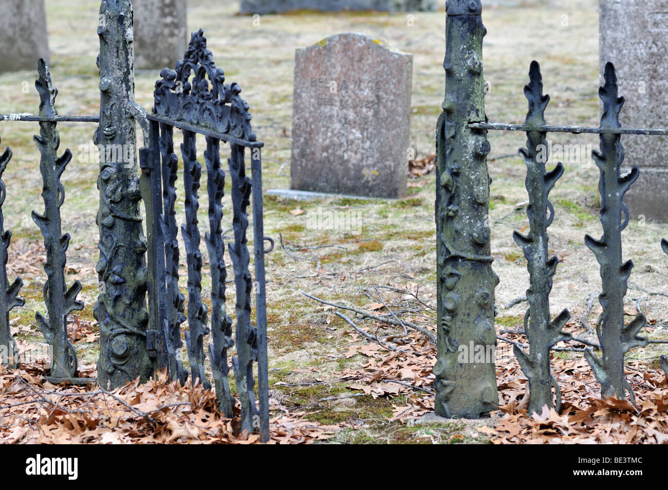 Wrought iron gate open to old cemetery grave plot and gravestones Stock
