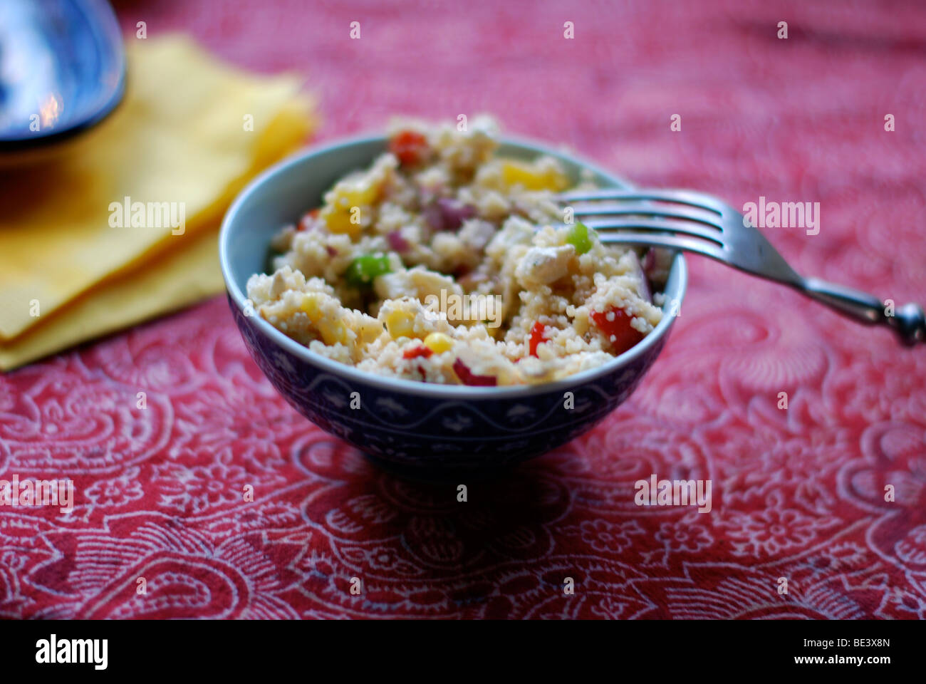 Couscous in blue bowl on red table cloth Stock Photo