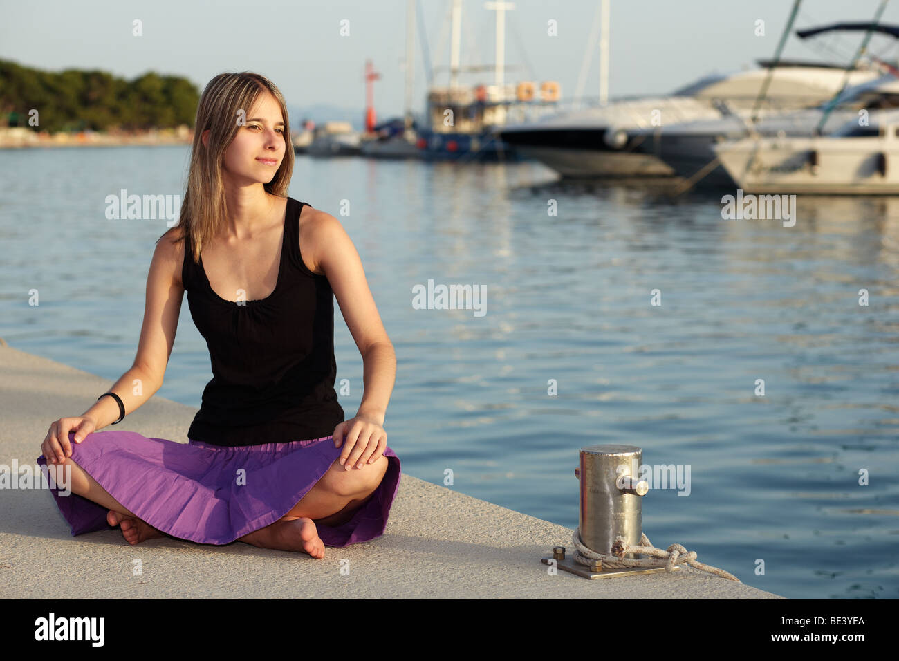 Young woman sitting in a harbour Stock Photo - Alamy