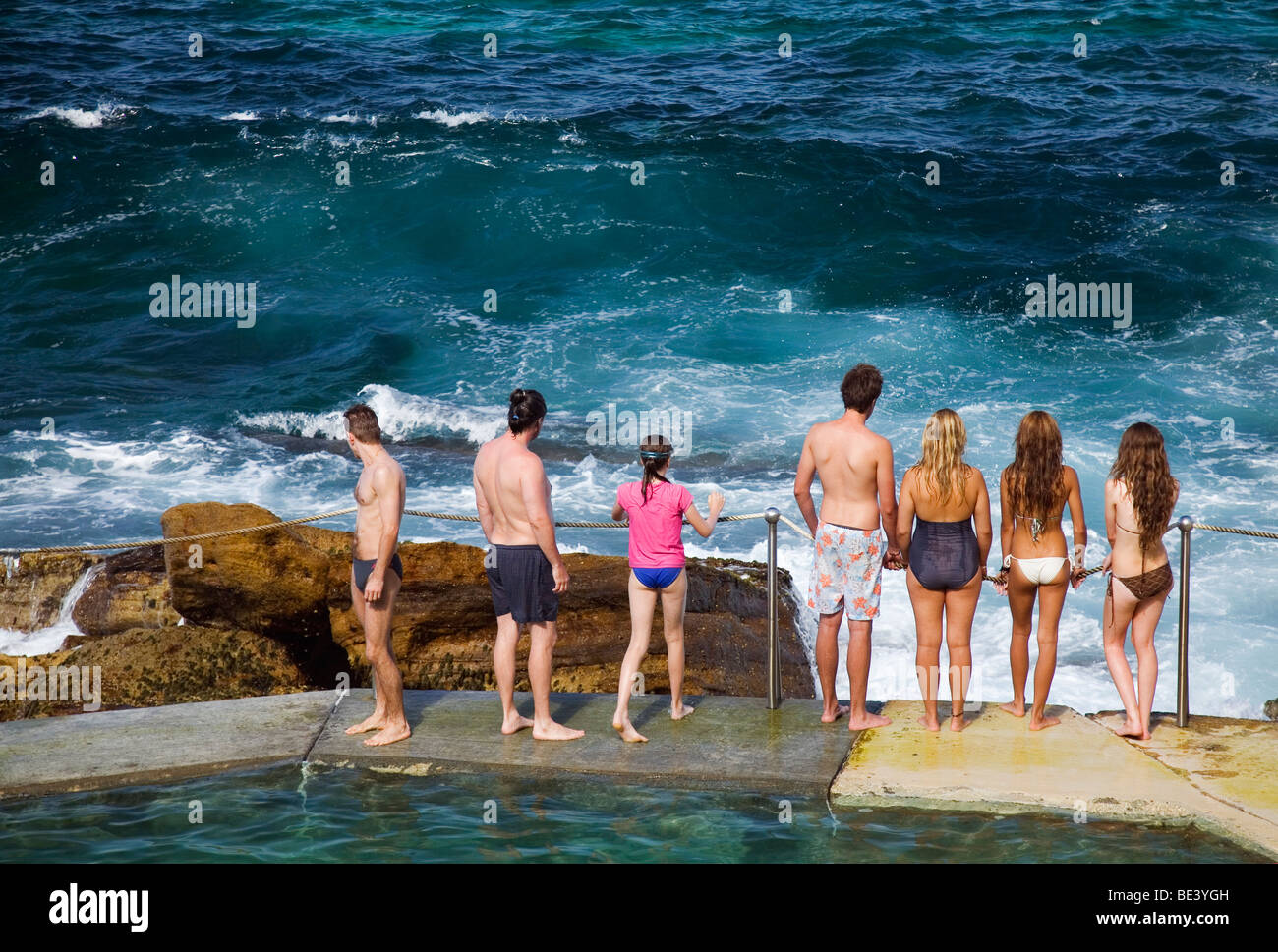 Swimmers watch the breaking waves at the Bronte Baths - ocean fillled pools at Bronte Beach. Sydney, New South Wales, AUSTRALIA Stock Photo
