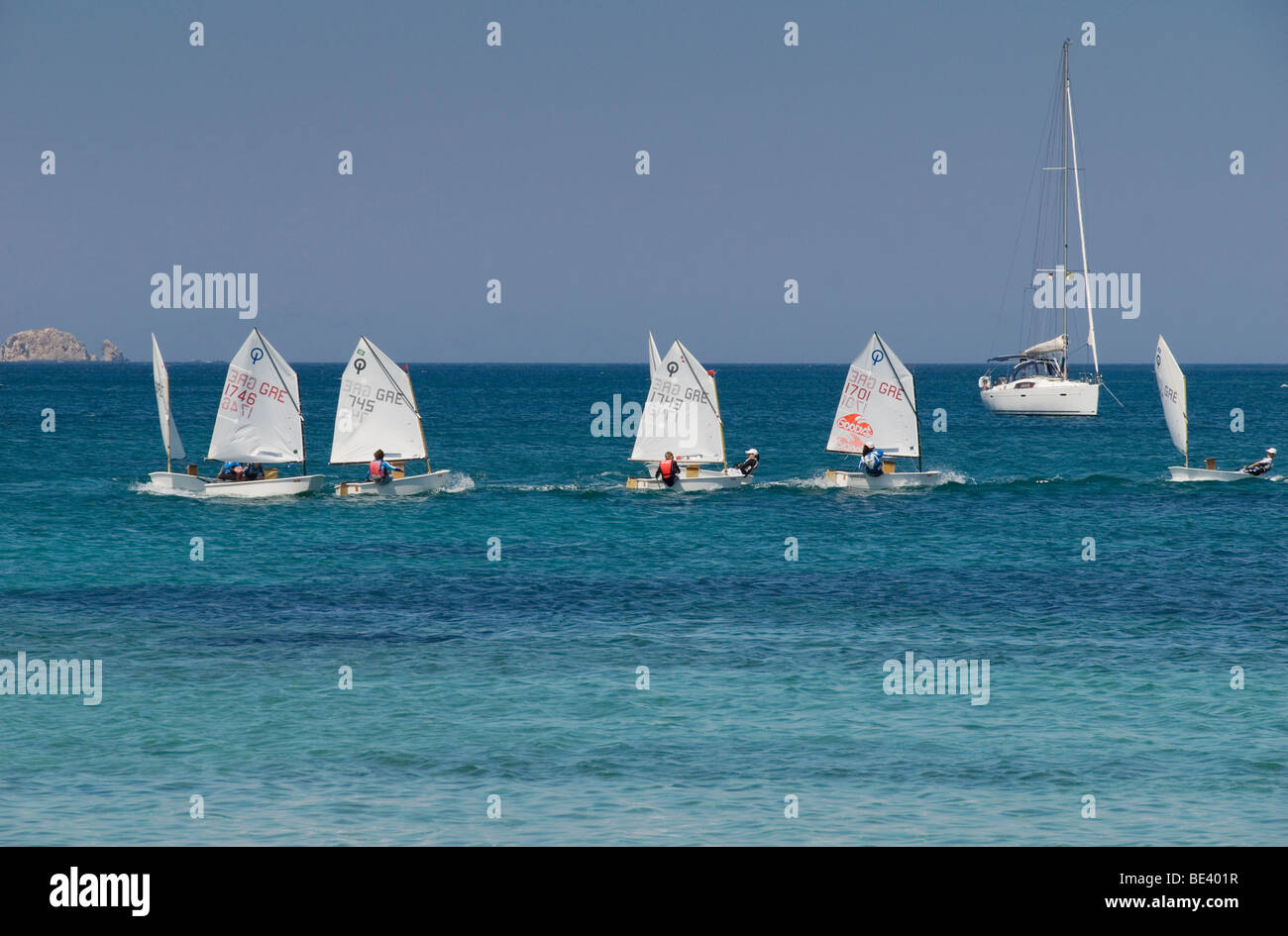 Children in Optimist class sailing dinghies racing off the coast of