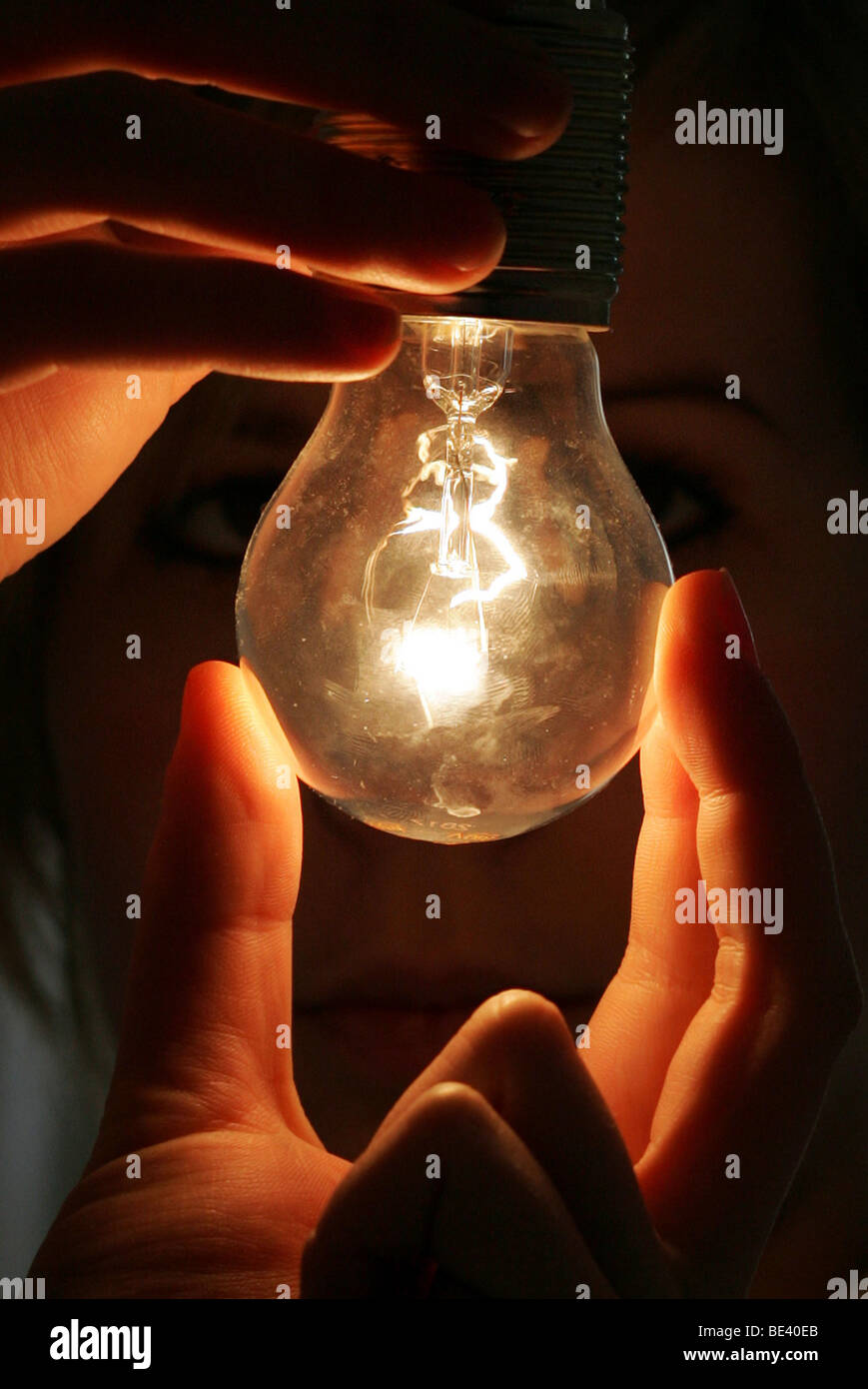 YOUNG WOMAN SCREWING A LIGHT BULB. Stock Photo