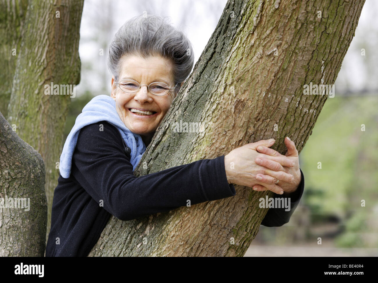 Seniorin lehnt an einen Baum Stock Photo