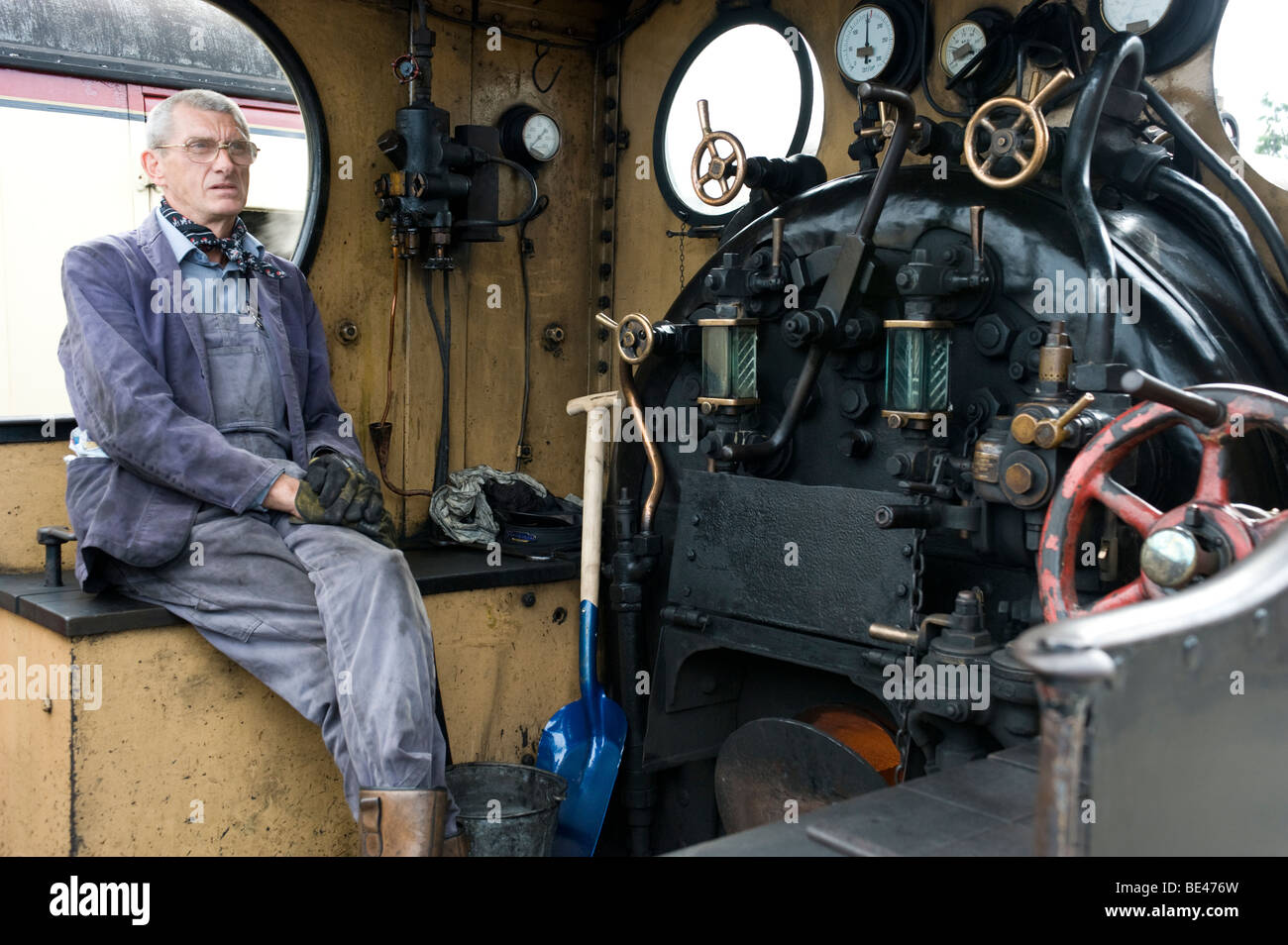 steam engine driver sitting in cab on footplate of steam train Stock Photo