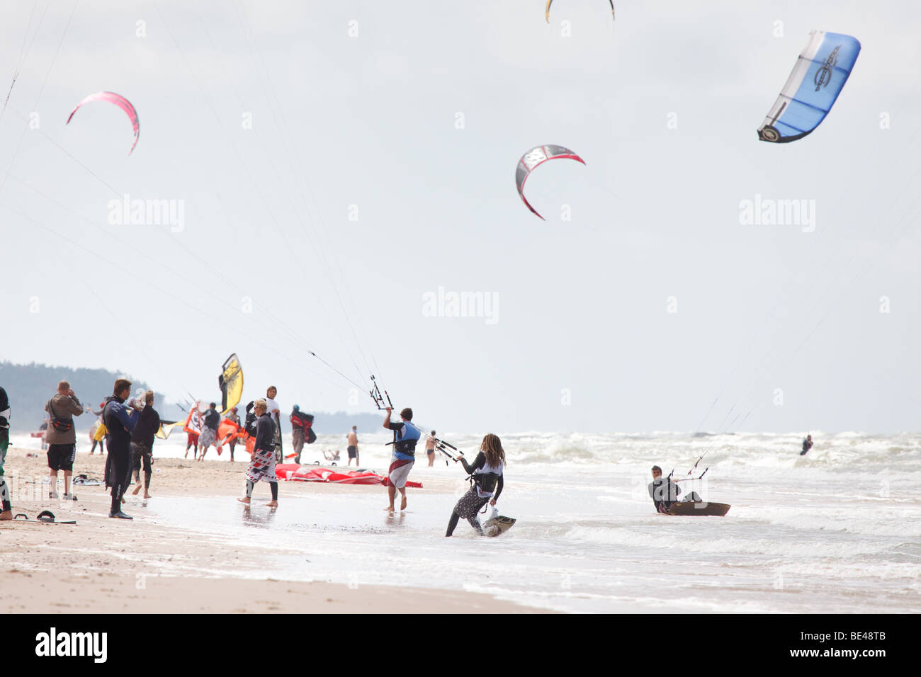 Kiteboarding competition with many active people and kites flying high in the sky Stock Photo