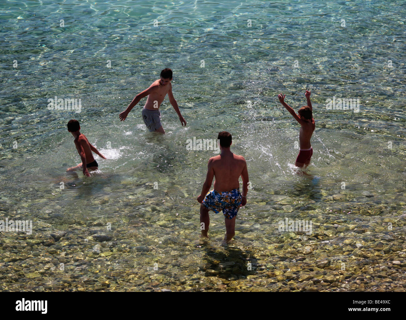 people splashing around in clear water at the beach Stock Photo