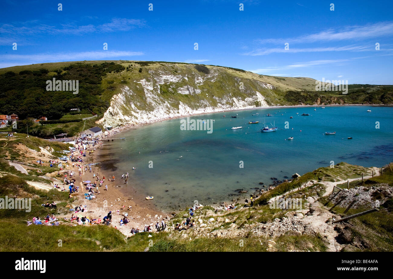 sunbathers tourists enjoying the summer sunshine down on lulworth cove dorset south england Stock Photo