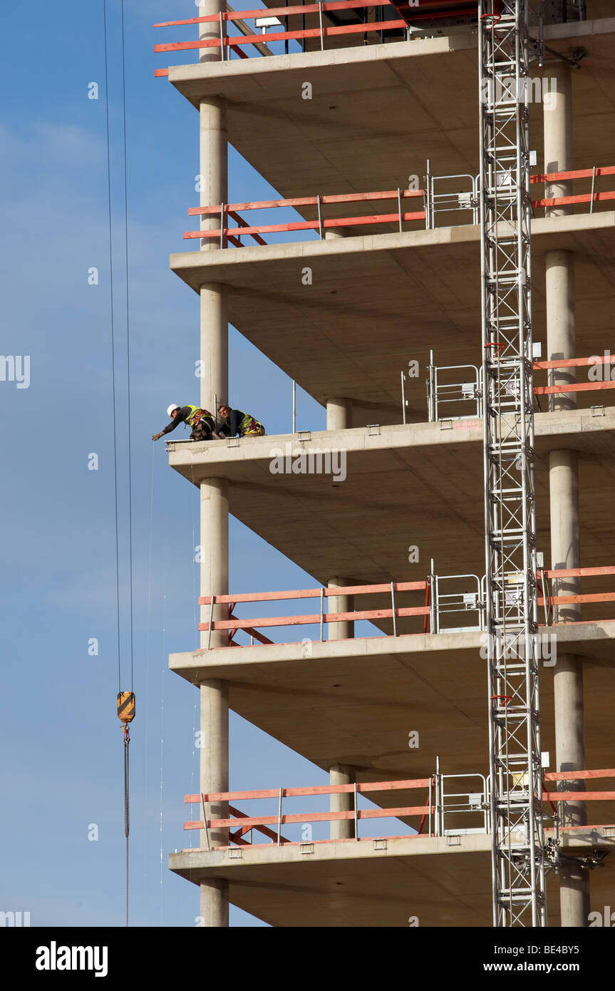 Construction workers fitting safety rails to s partly built office ...