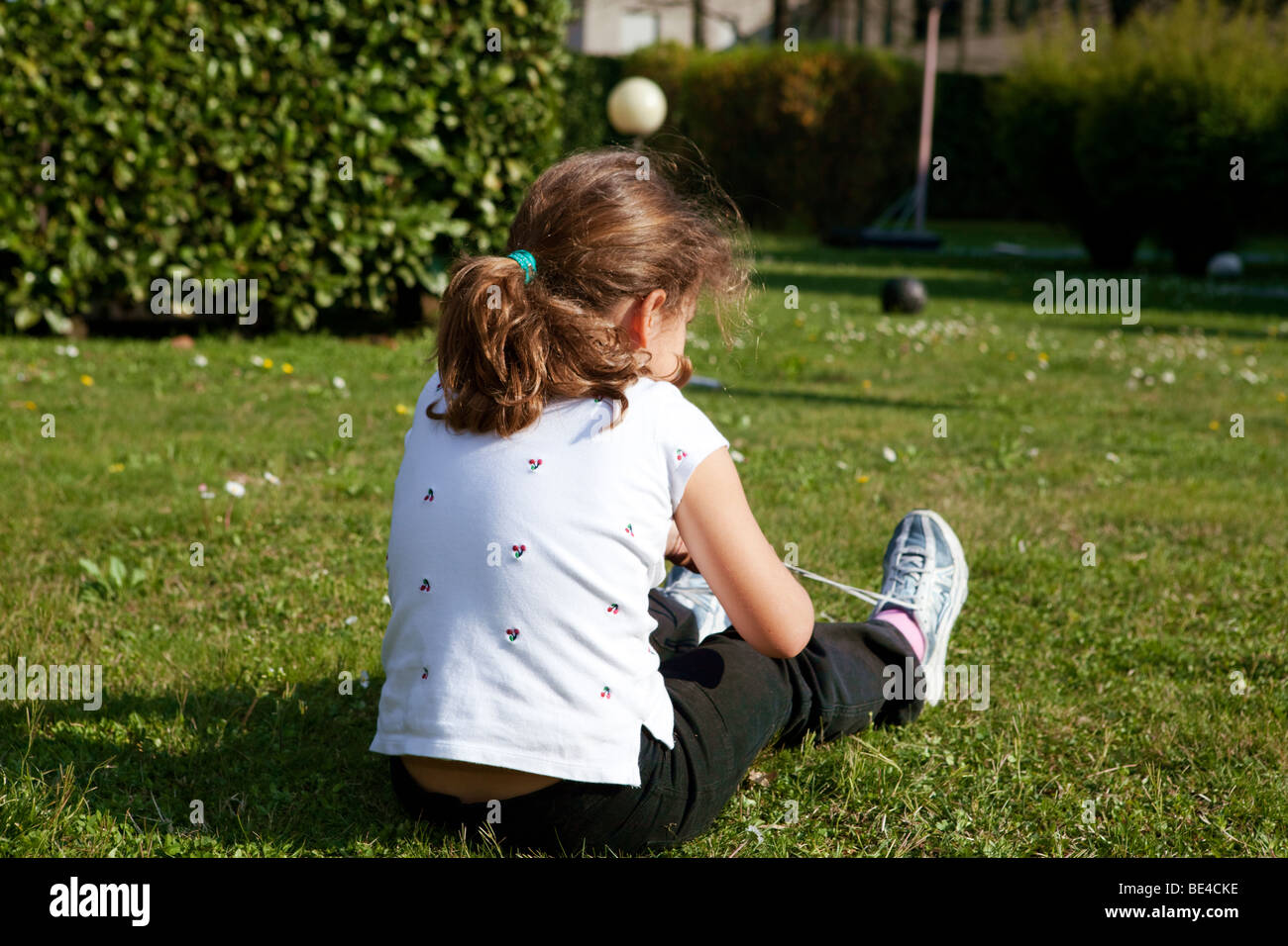 Young schoolgirl fixing her shoe laces in the garden Stock Photo Alamy
