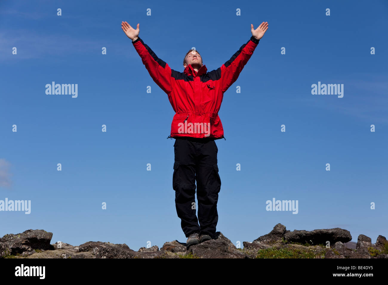 A man arms outstretched celebrating success at the top of a mountain