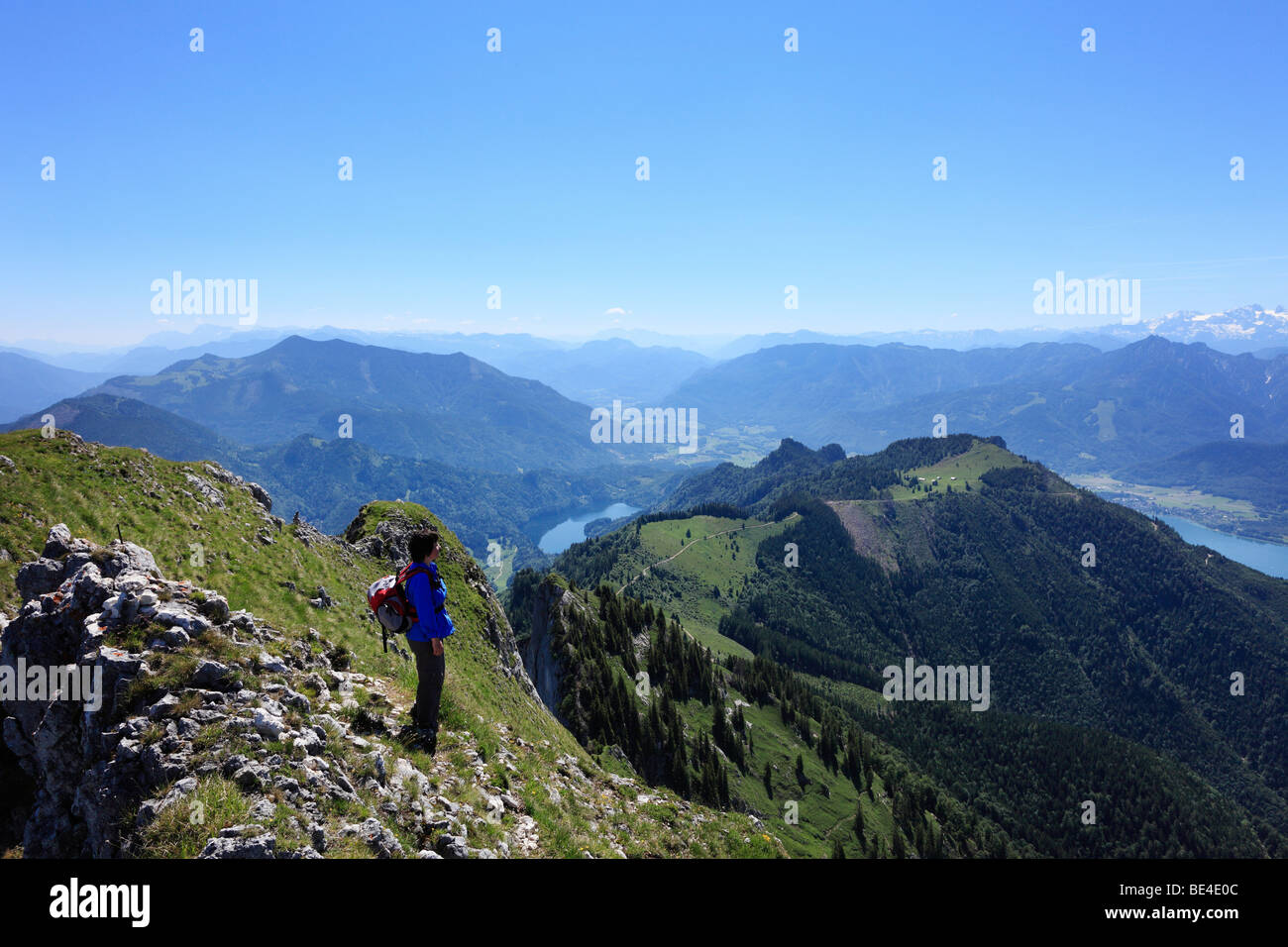 Woman with a backpack on Mt. Schafberg, Schwarzensee lake in the middle, on the right Wolfgangsee lake, Salzkammergut region, S Stock Photo