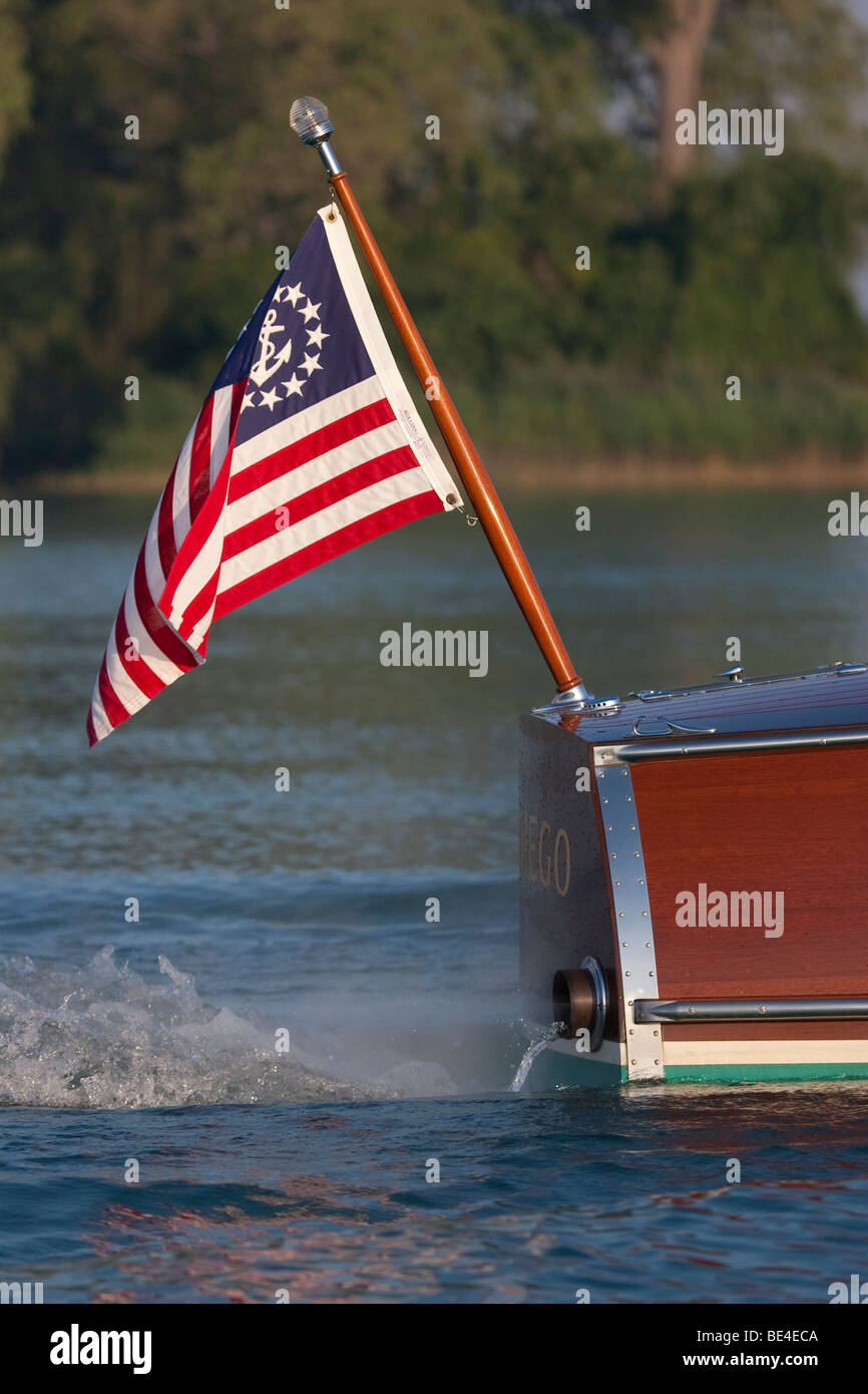 The mast and flag at the stern of a wooden boat cruising at low speed