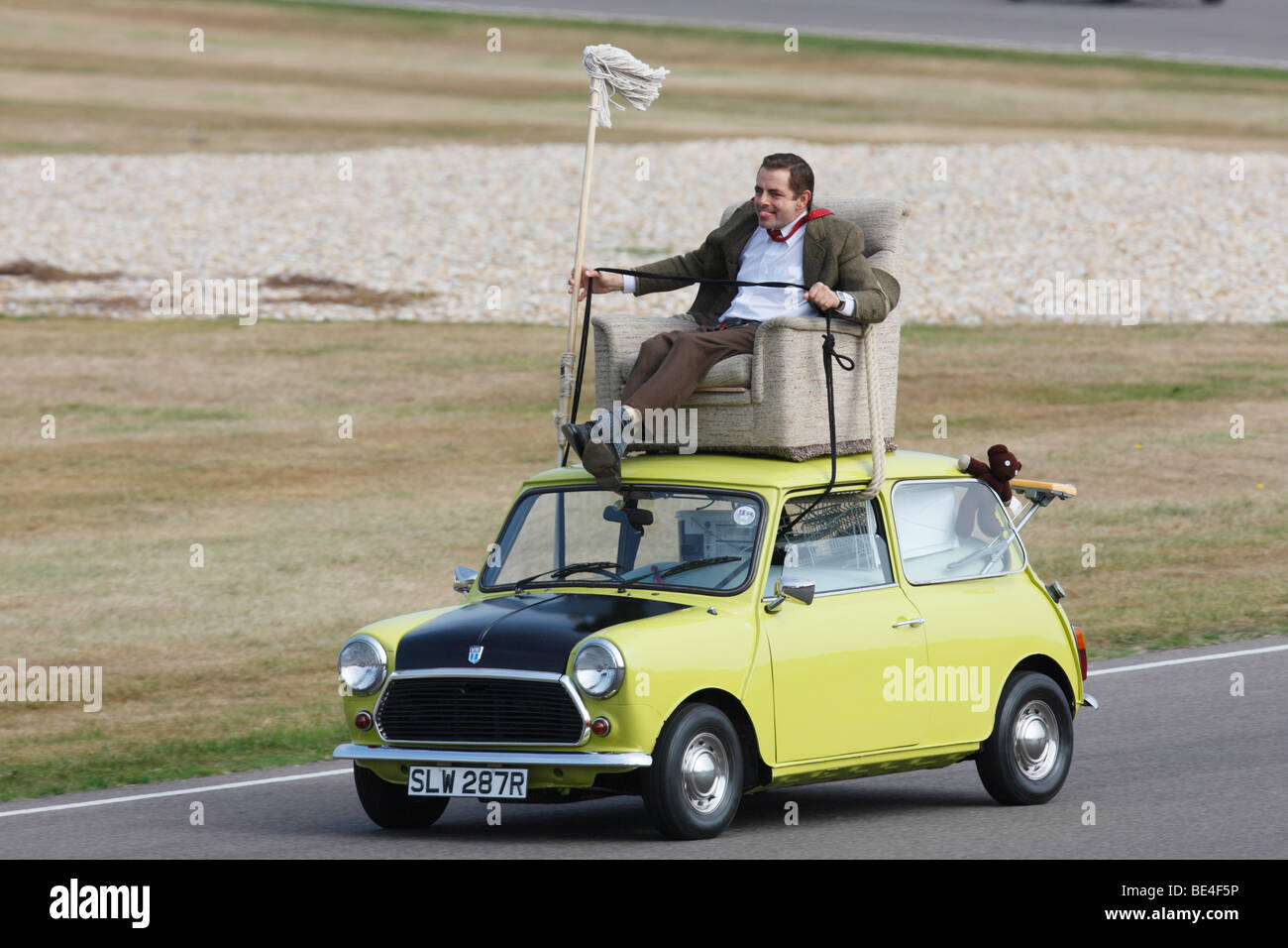 Mr Bean AKA Rowan Atkinson driving a mini from a roof armchair Stock Photo