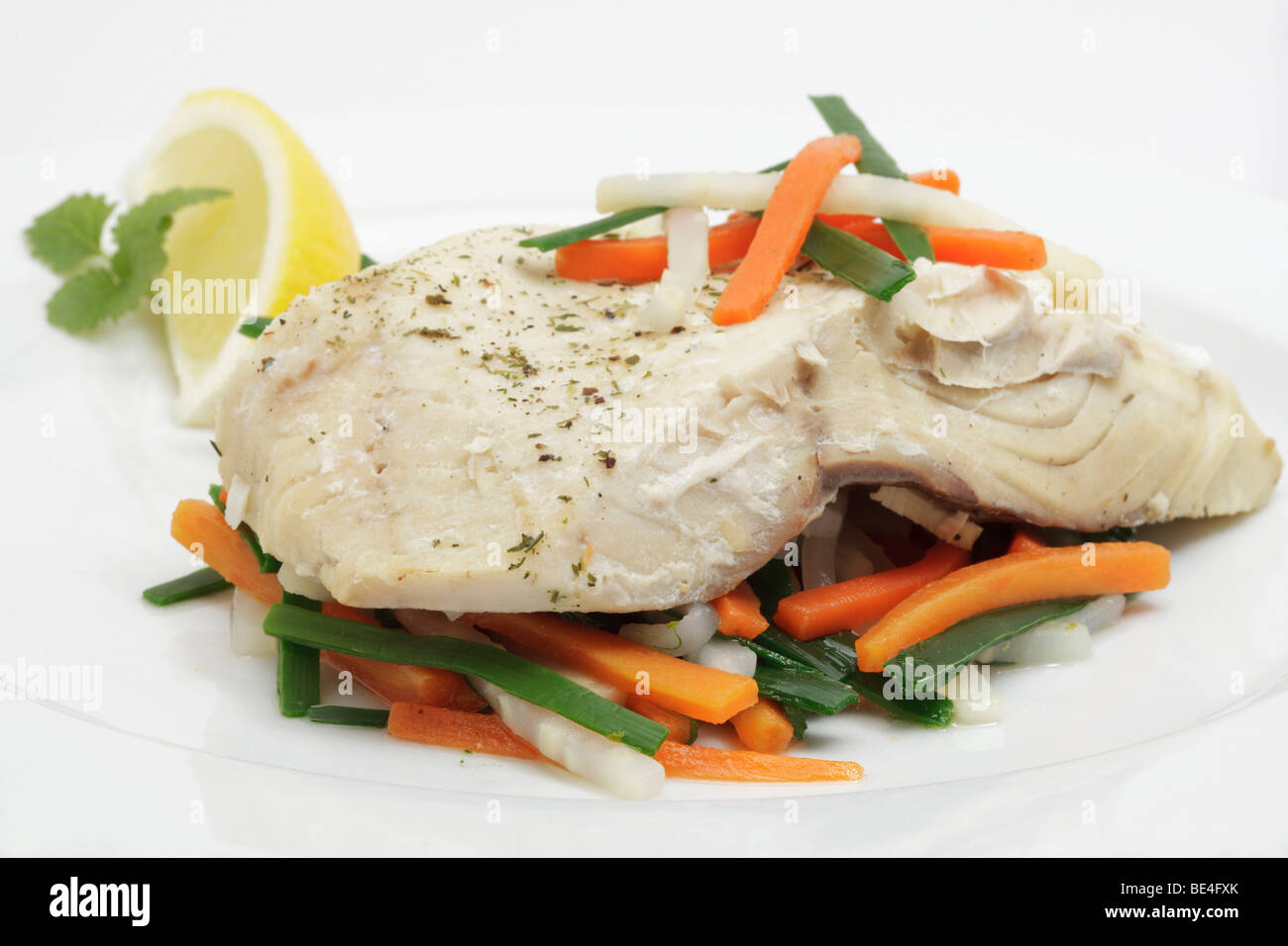 Steamed Saithe fillet on a bed of colourful vegetables Stock Photo