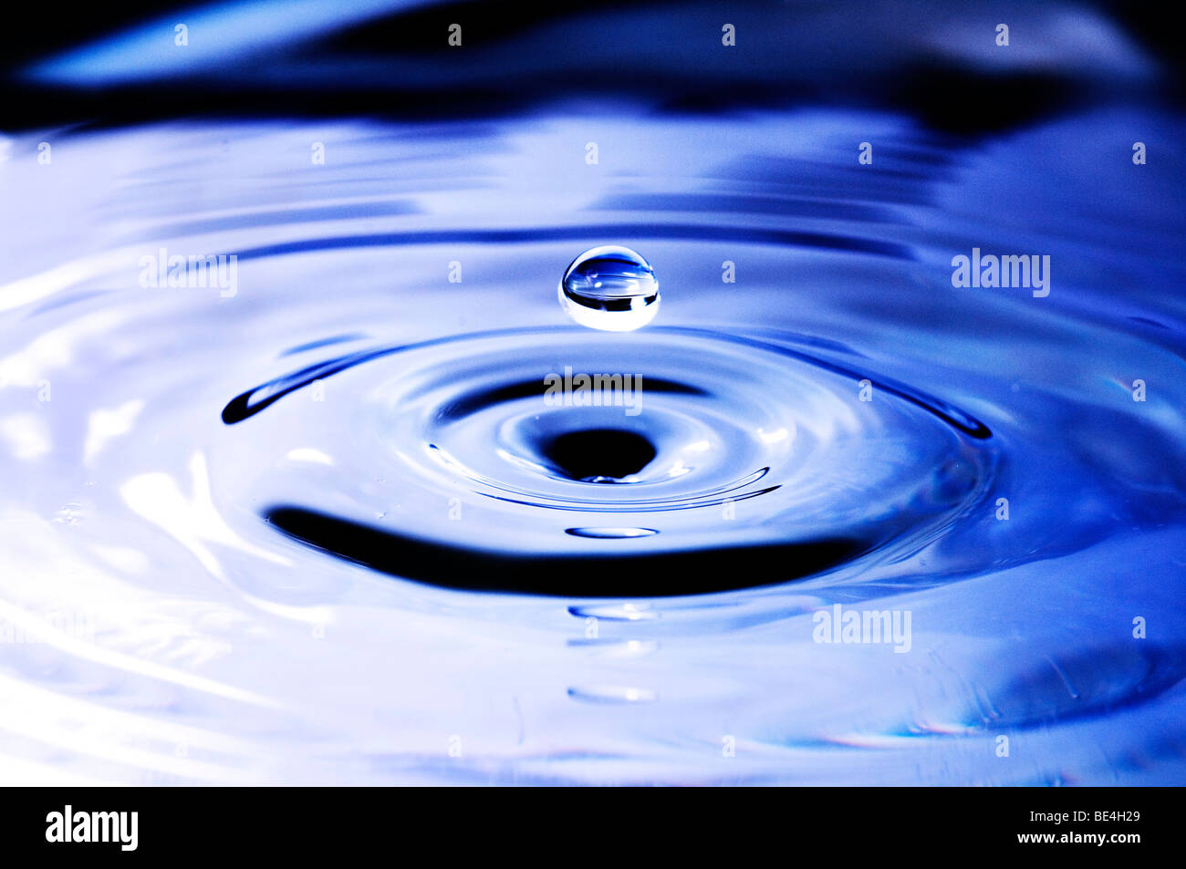 Water drops onto a water surface with concentric waves, close-up Stock Photo