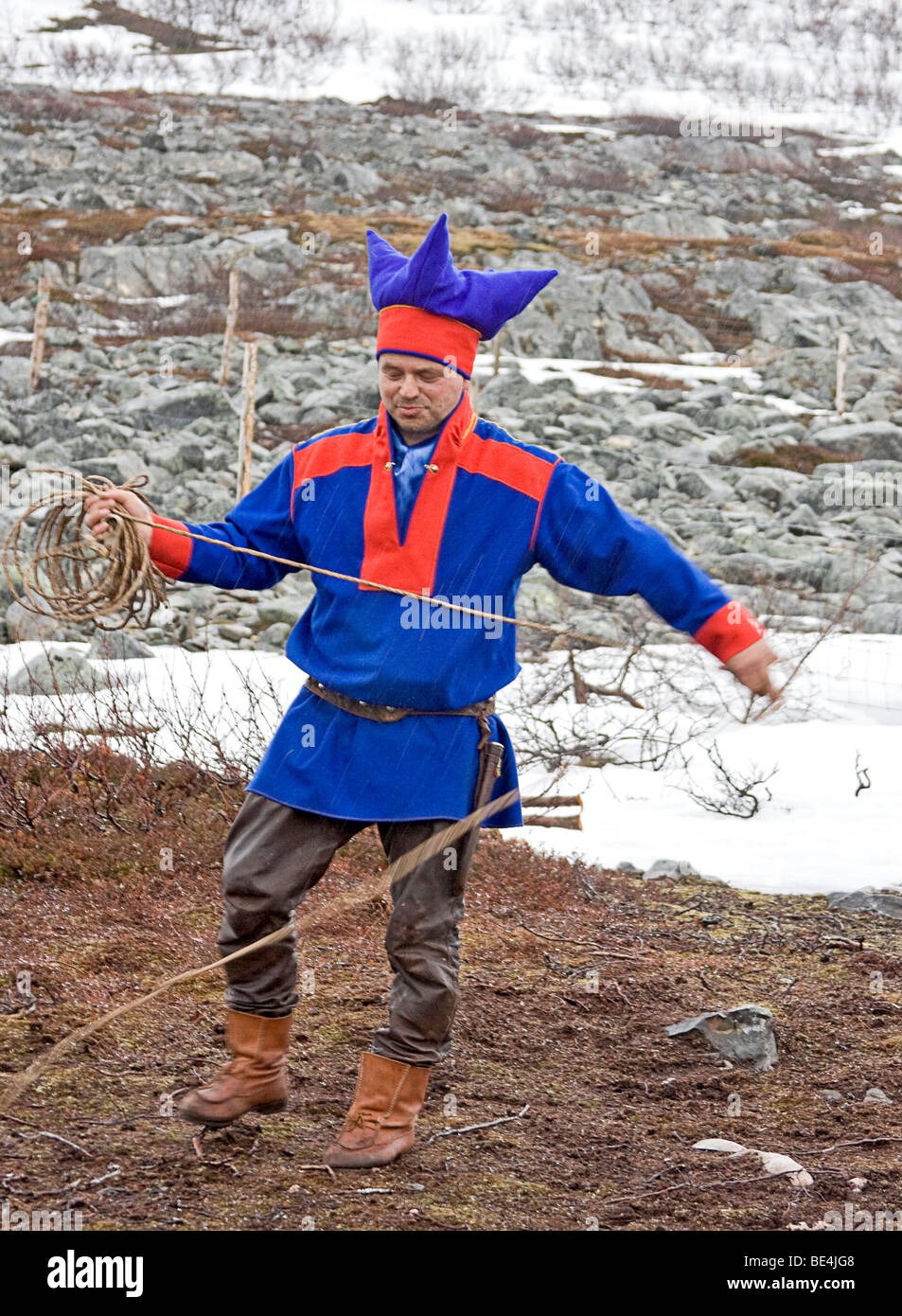 Middle aged Sami man in traditional clothing demonstrates techniques for lassoing reindeer at his camp Stock Photo