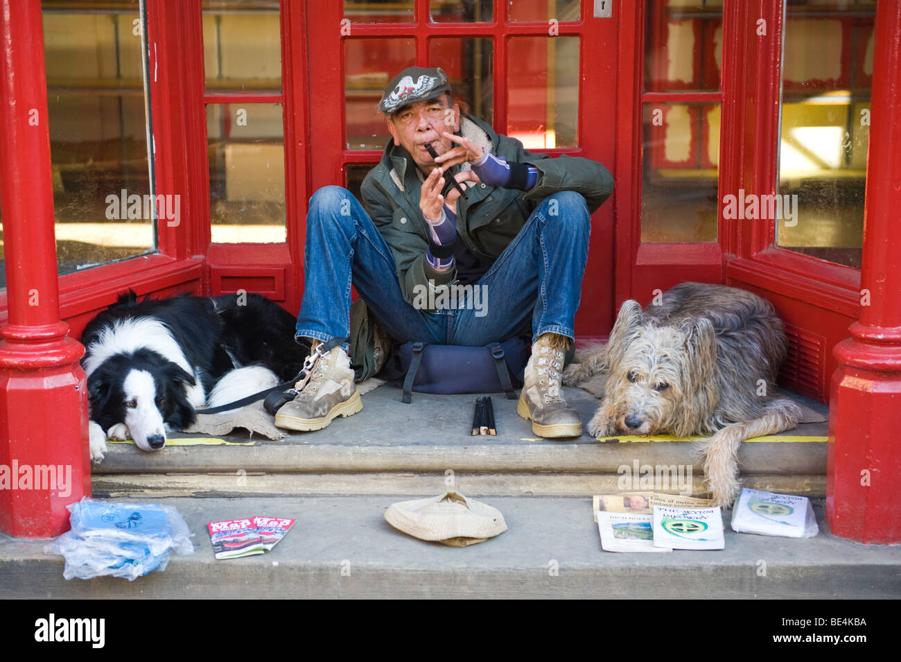 Man sat in doorway playing flute with two dogs during Ludlow Food Festival Shropshire England UK Stock Photo