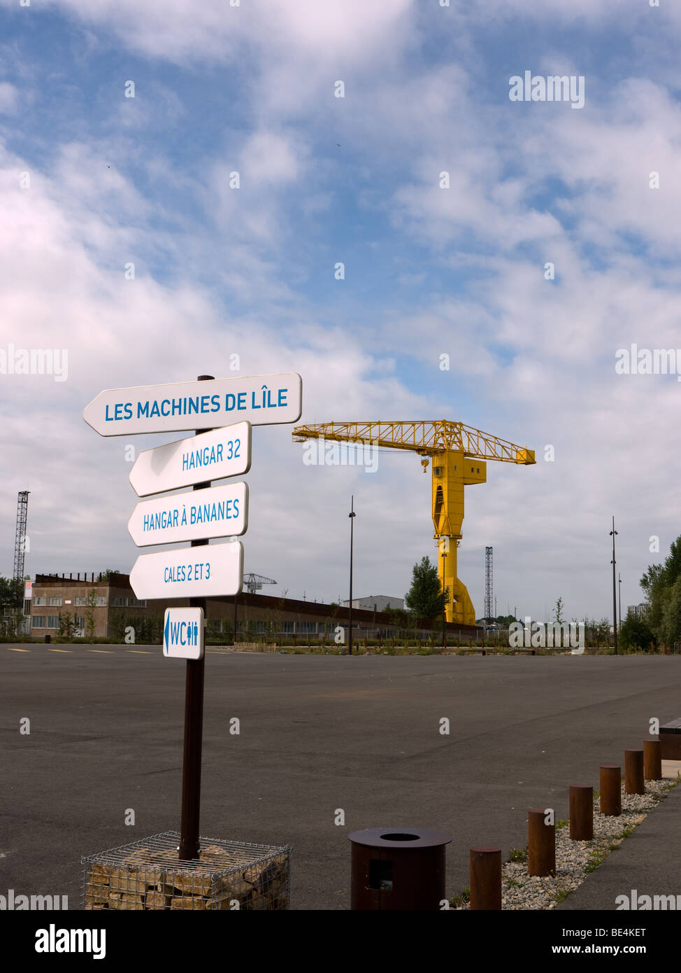 A sign points towards les machines de l'ile in Nantes, France with the distinctive grue titan in the background. Stock Photo