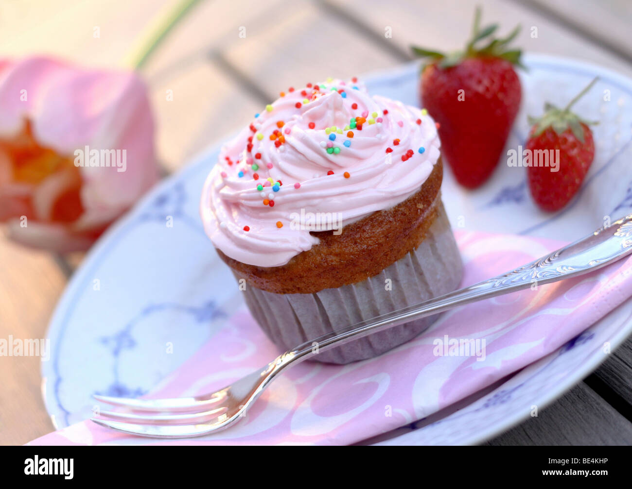 Cupcake muffin with cream, strawberries and pearl sugar on plate Stock Photo