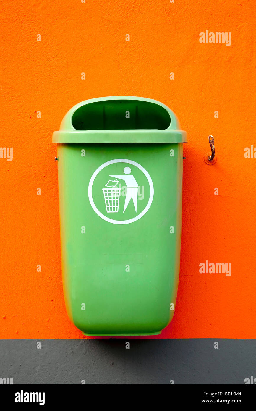 Green trash can on an orange wall in Neutraubling, Bavaria, Germany, Europe Stock Photo