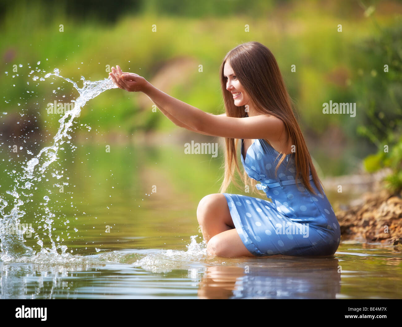 Young woman on a river bank playing with water. Stock Photo