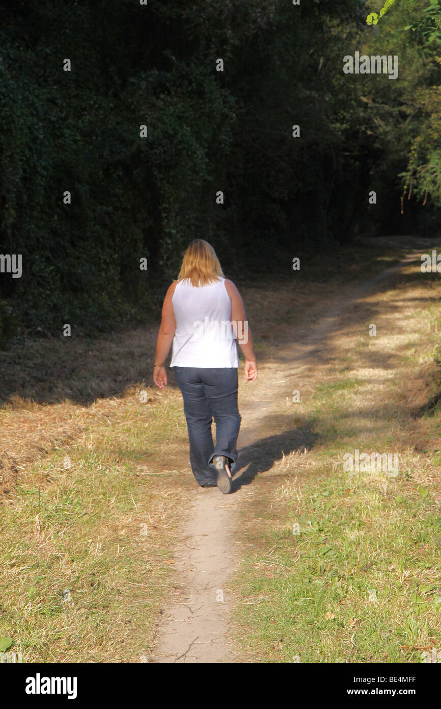 Lone women walking along deserted country path Stock Photo
