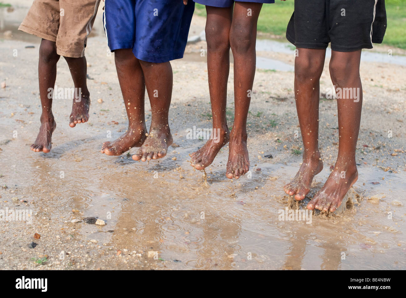 Indian children jumping and splashing in a puddle of water. Andhra Pradesh, India Stock Photo