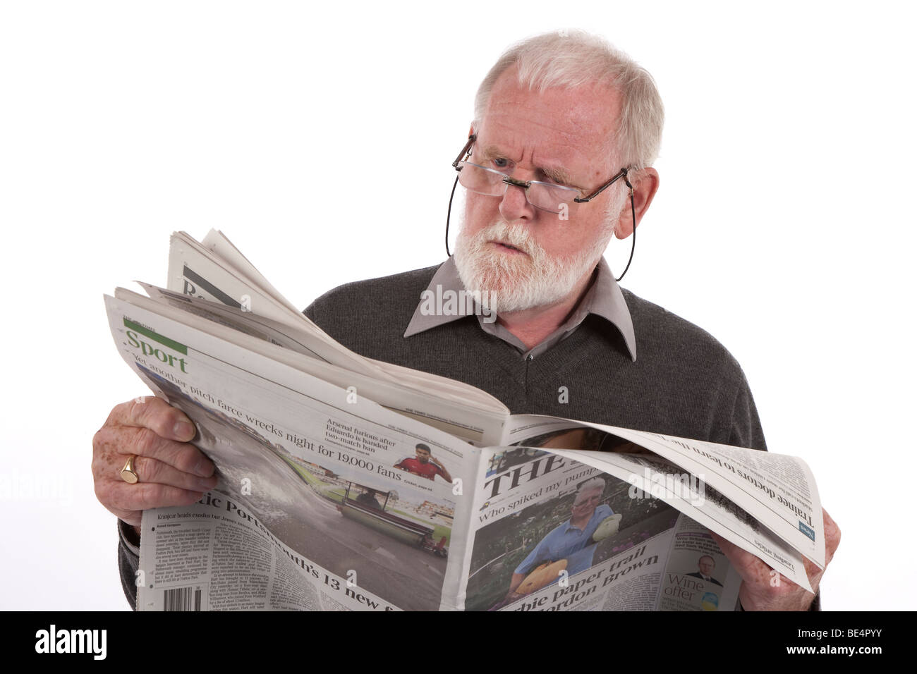 Older man reading newspaper with angry expression. Stock Photo