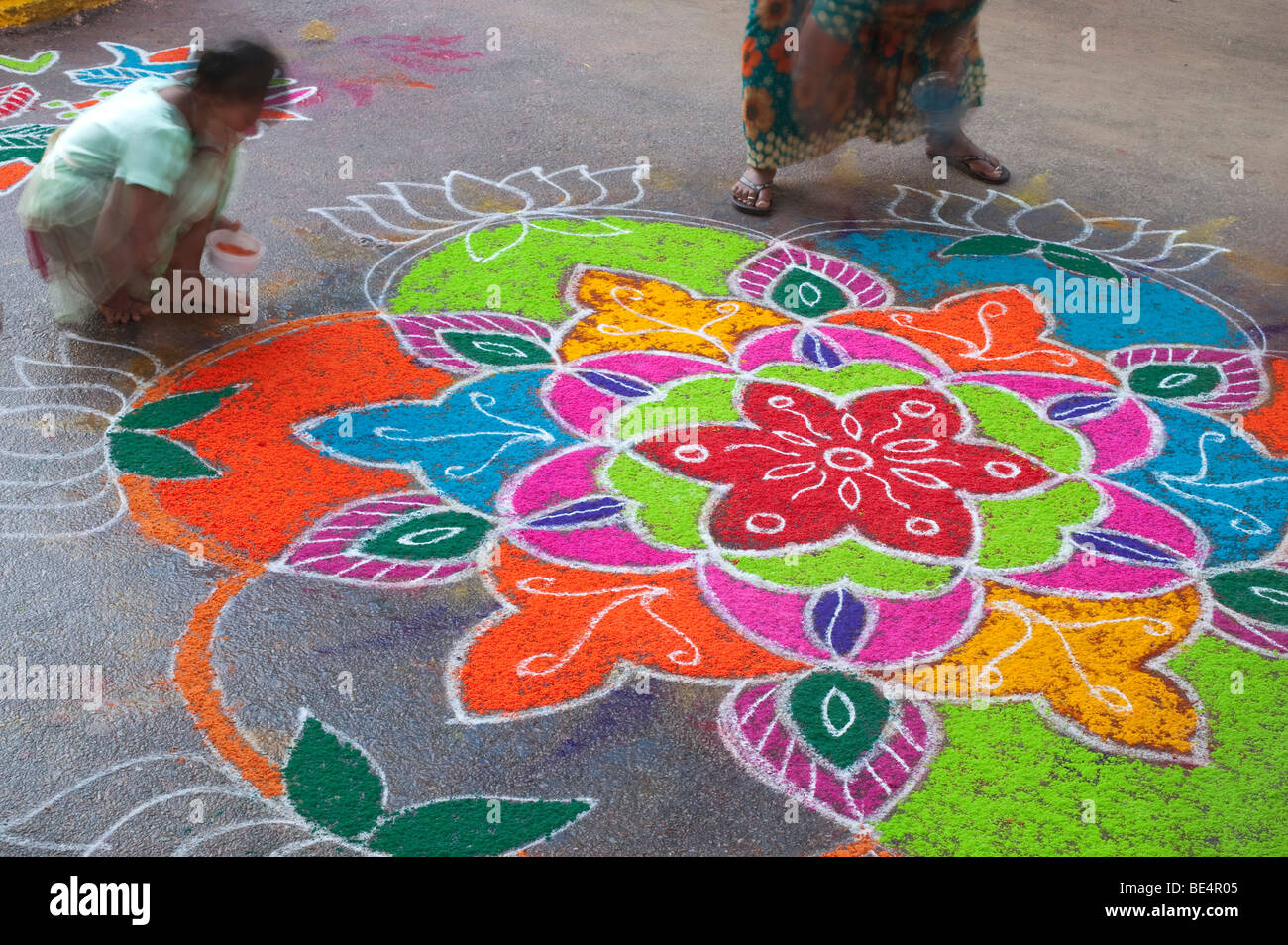 Indian women making a Rangoli festival design in an Indian street at the hindu festival of Dasara. Puttaparthi, Andhra Pradesh, India Stock Photo