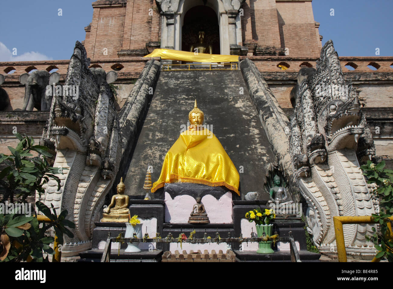 The golden statue of the Buddha draped in golden robes with snakes in front of the stupa of Wat Chedi Luang, Chiang Mai, Northe Stock Photo
