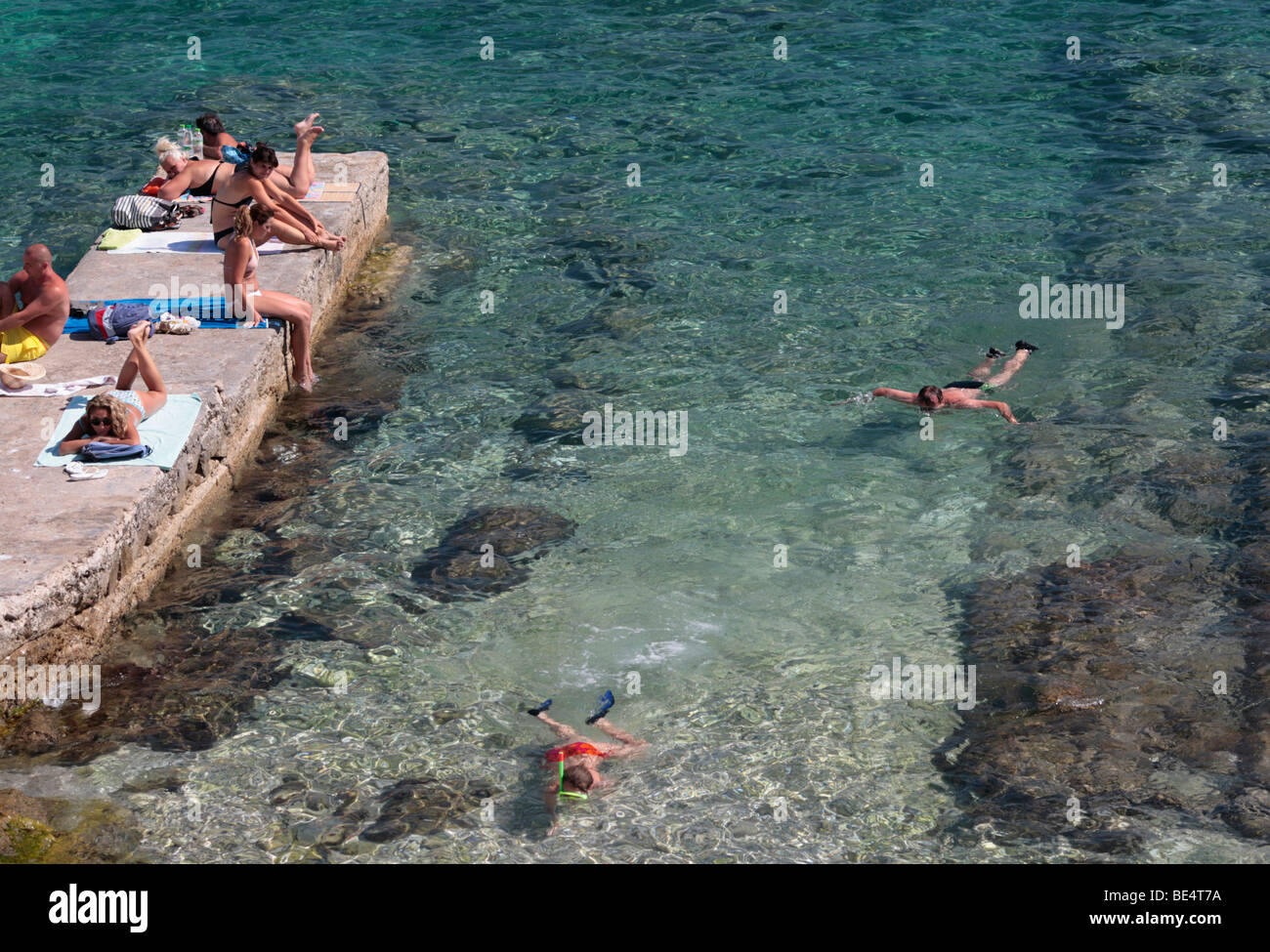 sunbathers and snorkellers in clear water Stock Photo